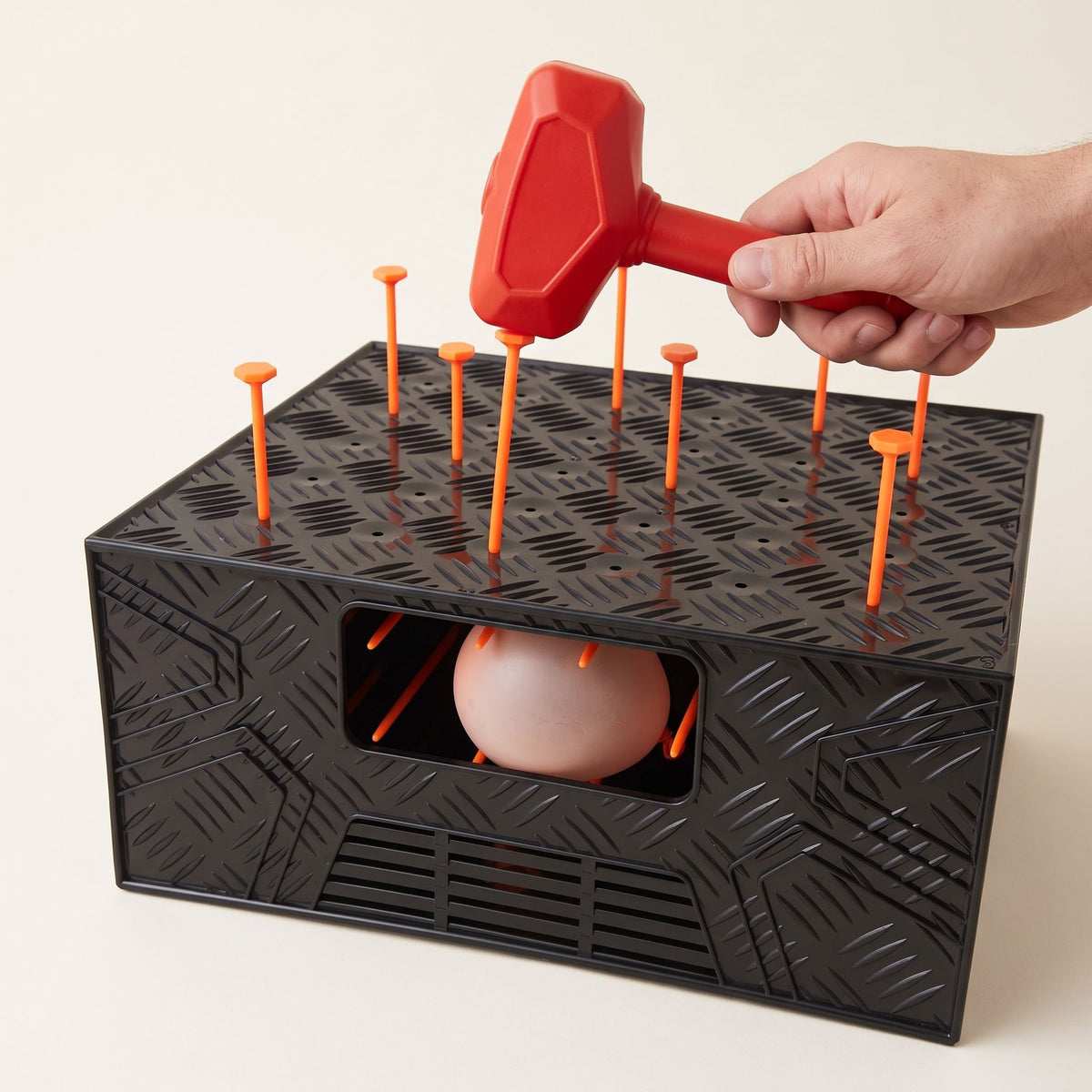 A hand holding the hammer over the nails on the LastPops box